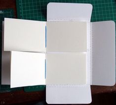 an open box with three cards inside on a table next to scissors and cutting mat