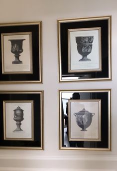 four black and white framed pictures hanging on the wall next to each other with vases in them