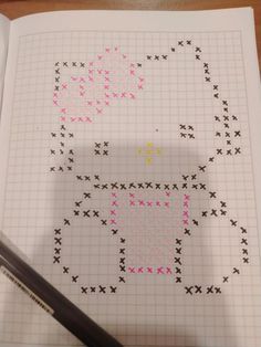 a cross - stitch pattern is shown on top of a piece of paper with a pen next to it