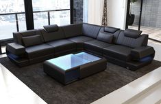 a modern living room with black leather couches and large windows overlooking the cityscape