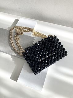 Set off and elevate any outfit with our beaded bag in classic black and gold. Each bag is handcrafted and individually woven with hundreds of beads, taking hours to craft. Carefully handwoven with the utmost care to ensure strength during use - and perfectly paired with our jewelry!  Details: Chain strap handle  Closed flap top Bag dimension: Length: 17 cm Width:  2.8 cm Height: 12 cm Short Handle drop: 23 cm Long Handle drop: 43cm Interior opening width: 15 cm **Due to the unique hand made-to-order nature of each purse, slight variations in colour or size can be expected.** Hand Beaded Bag, Crystal Bags, Strap Purse, Crystal Clutch, Pearl Bag, Beaded Bag, Beaded Purses, Purse Strap, Gothic Style