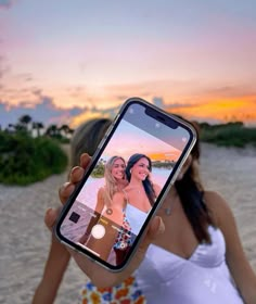 a woman taking a selfie with her cell phone on the beach at sunset or sunrise