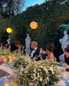 a group of people sitting at a table with flowers and candles in front of them