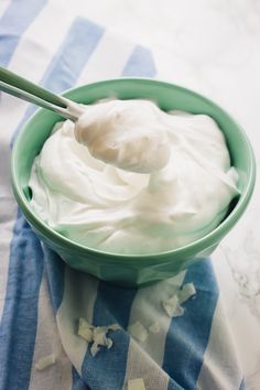 a green bowl filled with whipped cream on top of a blue and white towel