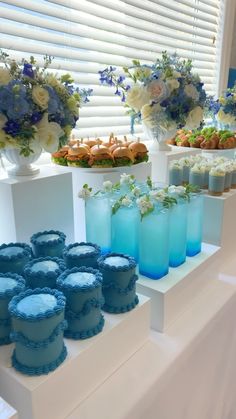 there are many desserts on the table with blue frosting and flowers in vases