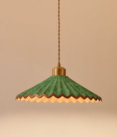 a green lamp hanging from a gold chain