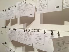 several pieces of paper are hanging on a clothes line with clips attached to it and pinned to the wall