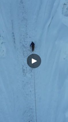 an aerial view of a person walking in the snow on skis and holding onto a rope