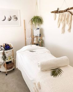 a white bed sitting next to a wooden shelf filled with plants and other items on top of it