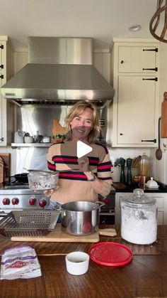 a woman standing in a kitchen with pots and pans