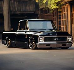 an old black pickup truck parked in front of a building