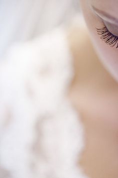 a woman's eye is reflected in the reflection of her cell phone while she has long eyelashes