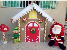 an outdoor christmas scene with santa claus and elves in front of a gingerbread house