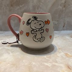 a coffee cup with a drawing of a cartoon character on the side and hearts around it