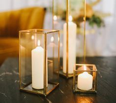 three candles are sitting in glass containers on a table with the caption shop new lanterns