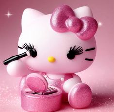 a hello kitty figurine sitting on top of a pink surface with glitter around it