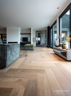 a living room with wood flooring and large windows