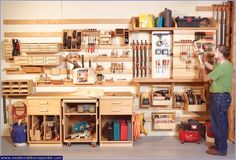 a man working in a garage with lots of workbenches and tools on the wall