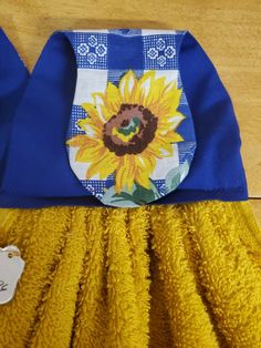 a blue and yellow dress with a sunflower on the front is sitting on a wooden floor