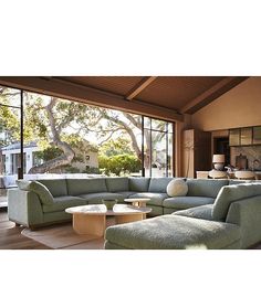 a living room filled with lots of furniture next to a large glass wall window overlooking a swimming pool