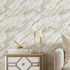 a white and gold marbled wallpaper in a living room with a chair, side table and lamp