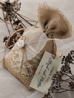 two small bags with tags on them sitting next to some dried flowers and twigs in the foreground