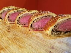 some meat rolls are lined up on a cutting board