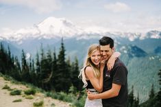 a man and woman hugging on top of a mountain