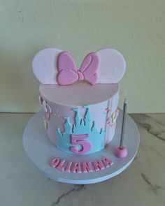 a birthday cake with pink and blue frosting on the top is decorated with minnie mouse ears