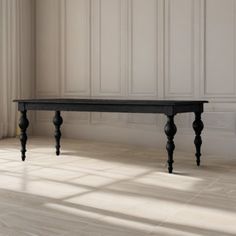 a black table sitting in the middle of a room next to a window with white walls