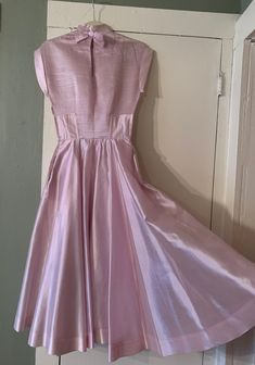 "Beautiful 1950s party dress, dreamiest iridescent pale pink color that I would almost called a faint lilac purple in certain lights as well. Though I'm not 100% certain I believe the material is a silk organza, at least partially, it's a bit heavier than a more sheer organza, but has that look and feel. So well made, high-end in both material and construction, my photos don't do it justice. Features a horizontally pin-tucked bodice, decoratively trimmed cap sleeves, mock neck, a keyhole back wi Pink Pleated Dress For Prom Season, Pink Full Skirt Prom Dress, Vintage Pink Ball Gown Dress, Pink Pleated Evening Dress For Formal Occasions, Fitted Pink Vintage Prom Dress, Pink Pleated Dress For Prom, Formal Pink Pleated Evening Dress, Feminine Pink Full Skirt Dress, Formal Pink Full Skirt Dress