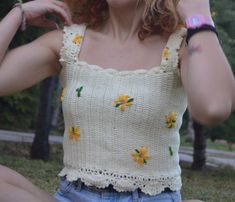 a woman sitting on the ground with her hands in her hair and wearing a flowered top