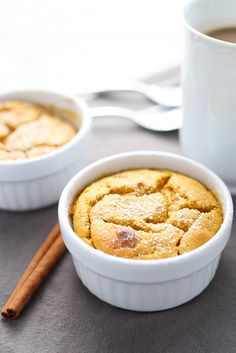 two white bowls filled with baked goods next to a cup of coffee and cinnamon sticks