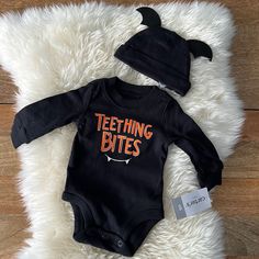 a baby bodysuit and hat sitting on top of a white rug