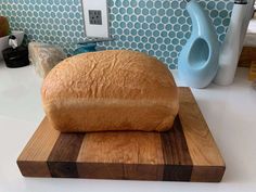 a loaf of bread sitting on top of a cutting board next to a blue vase