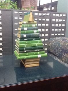 a stack of green books sitting on top of a table next to a pile of folders