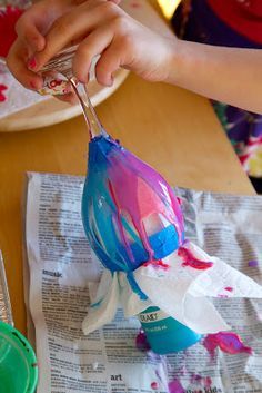 a child is painting an origami flower with watercolors on newspaper paper