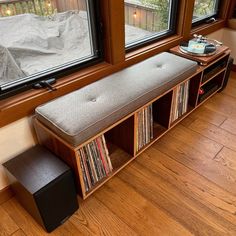 a wooden bench sitting next to a window filled with vinyl records