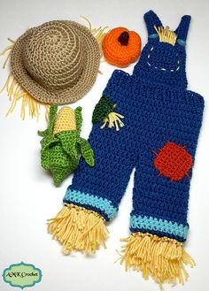 a crocheted blue overall and hat next to an orange ball