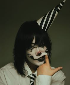 a man with black and white makeup is wearing a striped clown mask on his face