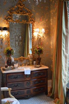 a bathroom with a vanity, mirror and chandelier on the wall above it