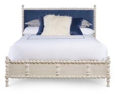 a white bed with blue and white pillows on it's headboard is shown