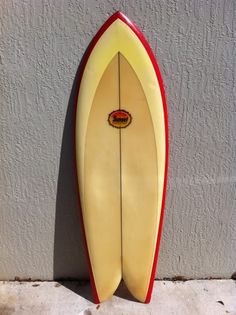 a yellow and red surfboard leaning up against a wall