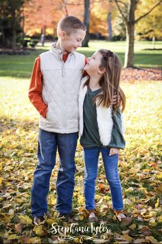 two young children are standing in the leaves