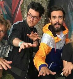 four people posing for the camera in front of a tree