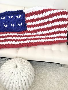 an american flag knitted blanket sitting on top of a white couch next to a round ottoman