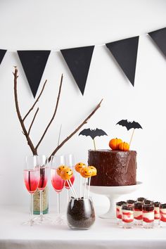 a table topped with a chocolate cake covered in icing next to cupcakes