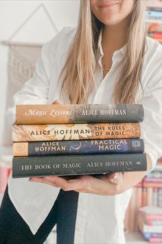 a woman holding four books in her hands