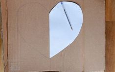 a cardboard box with a heart cut out of it and a pen sticking out of the hole