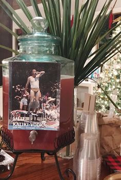 a glass jar filled with liquid sitting on top of a wooden table next to a christmas tree